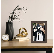 Decoratieve fotolijst met foto van een afgestudeerde op een tafel met decoraties.