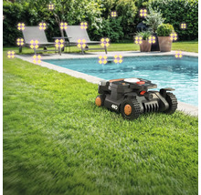 Scene met een gazonrobot naast een zwembad, omgeven door tuinmeubelen en planten.