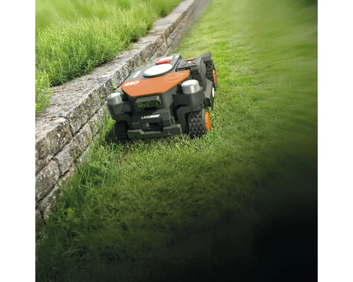 Landroid robotmaaier op gazon naast een muur