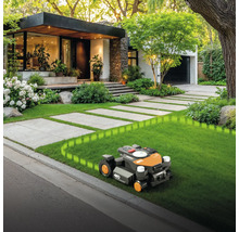 Robotmaaier op gazon voor huis met betegeld pad