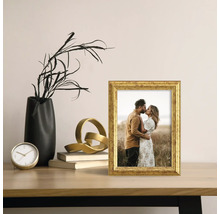 Decoratieve scène met een gouden fotolijst, een zwarte vaas en een gouden sculptuur