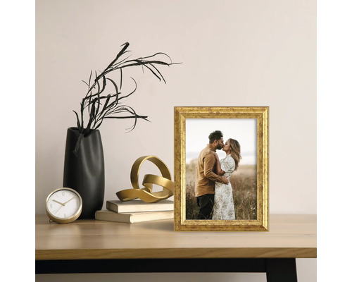 Decoratieve scène met een gouden fotolijst, een zwarte vaas en een gouden sculptuur