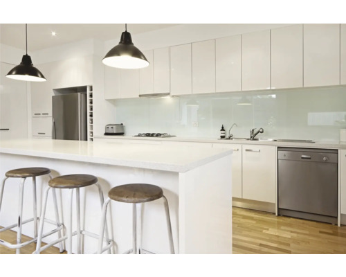 Lichte keuken met kookeiland, barkrukken en moderne apparatuur.