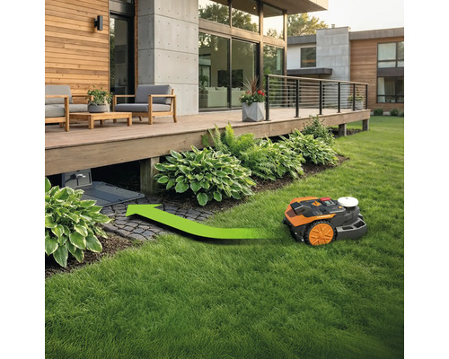 Robotmaaier rijdt met groene pijl naar laadstation onder een houten terras