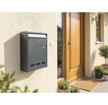 Antracietkleurige brievenbus aan een huismuur naast een voordeur