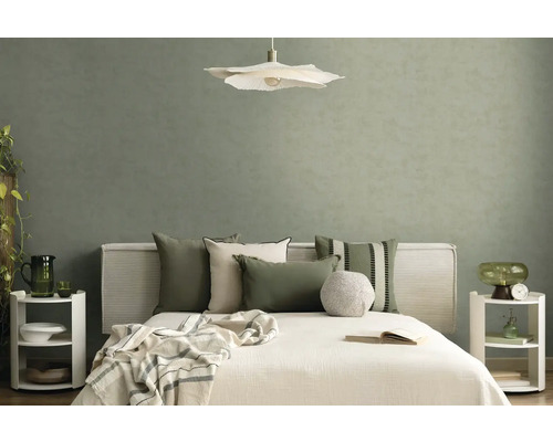 Moderne slaapkamer met saliegroen behang met textuur, wit bed met sierkussens, bloemvormige hanglamp en minimalistische nachtkastjes.