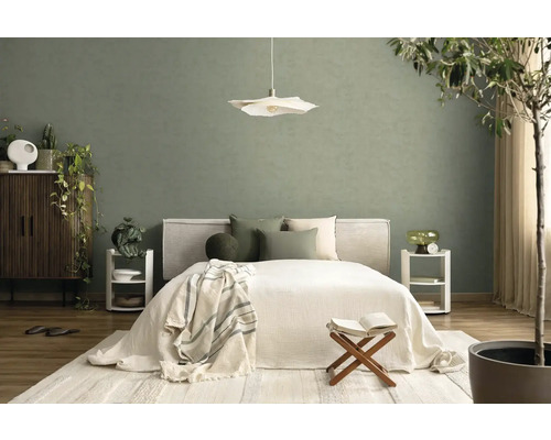Moderne slaapkamer met groene muur, wit bed, hanglamp en licht tapijt in een georganiseerde, natuurlijke sfeer.