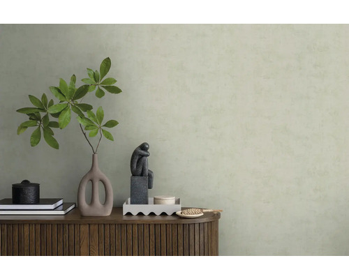 Behang met structuur in lichtgroen achter een houten dressoir met vaas, takken en een beeldje in een minimalistisch interieur.