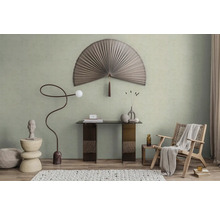 Modern ingerichte kamer met lichtgroene muurverf, een grote decoratieve waaier, een consoletafel en een fauteuil van vlechtwerk.