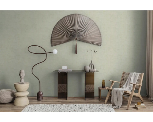 Modern ingerichte kamer met lichtgroene muurverf, een grote decoratieve waaier, een consoletafel en een fauteuil van vlechtwerk.