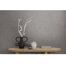 Wand met gestructureerd behang met betonlook achter een houten consoletafel met zwarte en witte keramische vazen en droge takken.