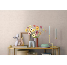 Helder gedecoreerde consoletafel met gerbera-vaas, fotolijst, ballonnenhond-sculptuur en minimalistische kandelaars voor een wand met textuur.