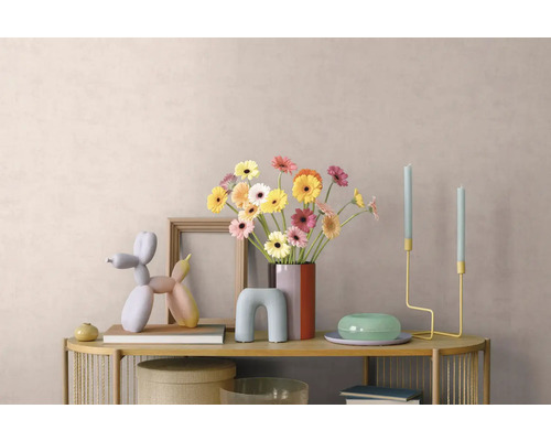 Helder gedecoreerde consoletafel met gerbera-vaas, fotolijst, ballonnenhond-sculptuur en minimalistische kandelaars voor een wand met textuur.