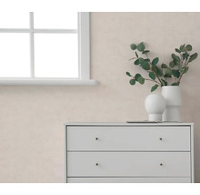 Licht, gestructureerd behang in een moderne kamer met een witte ladekast, raam en eucalyptustakken in witte vazen.