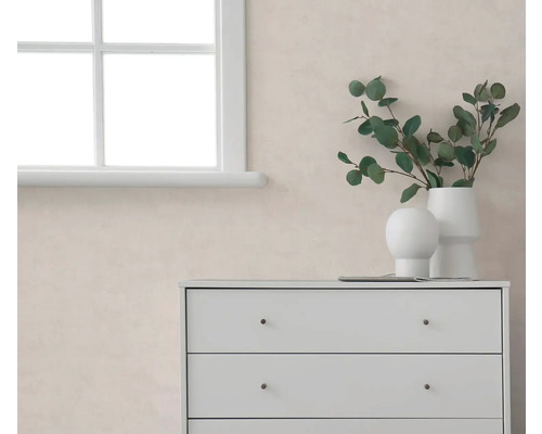 Licht, gestructureerd behang in een moderne kamer met een witte ladekast, raam en eucalyptustakken in witte vazen.