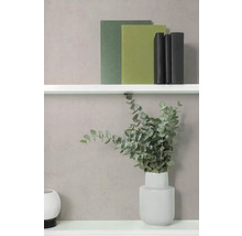 Getextureerde wand met witte planken, boeken, een vaas met eucalyptustakken en een rond decoratie-object.