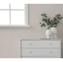 Lichte kamer met witte ladekast, eucalyptus takken in witte vazen en raam voor een muur met textuur.