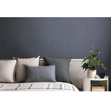 Slaapkamer met donkergrijs gestructureerd behang, bed met diverse kussens en een bijzettafel met een kamerplant.