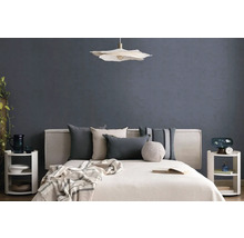 Moderne slaapkamer met bed, diverse kussens, een hanglamp en nachtkastjes voor een muur met textuur.