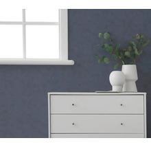 Donkerblauw gestructureerd behang op een muur in een kamer met een witte ladekast en een raam.