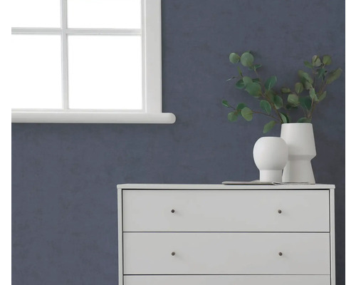 Donkerblauw gestructureerd behang op een muur in een kamer met een witte ladekast en een raam.