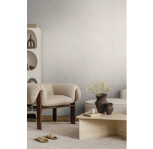 Lichte woonkamer met gestructureerde wandafwerking, moderne houten fauteuil, stenen salontafel en licht tapijt.