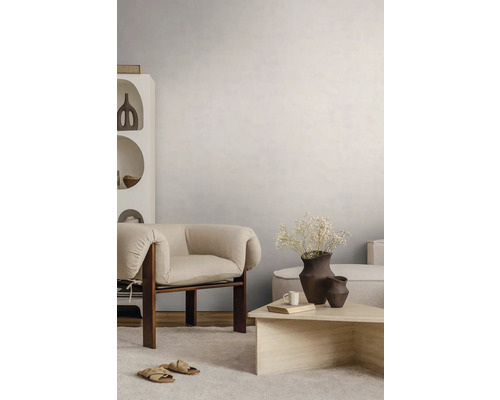 Lichte woonkamer met gestructureerde wandafwerking, moderne houten fauteuil, stenen salontafel en licht tapijt.