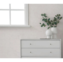 Lichte kamer met een wit raam, een lichte muur en witte ladekast, gedecoreerd met vazen en eucalyptustakken.