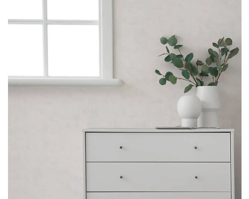 Lichte kamer met een wit raam, een lichte muur en witte ladekast, gedecoreerd met vazen en eucalyptustakken.