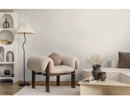 Licht ingerichte woonkamer in moderne stijl met houten fauteuil, vloerlamp met geplooide kap en een witte kast met organische vormen.