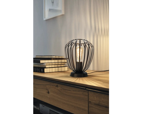 Decoratieve tafellamp met een lampenkap van metalen spijlen en een gloeilamp.