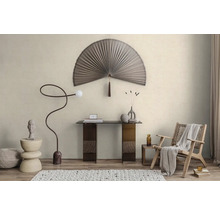 Lichte minimalistische kamer met waaiervormige wanddecoratie, glazen tafel, gebogen vloerlamp en houten fauteuil op een gestructureerd tapijt.