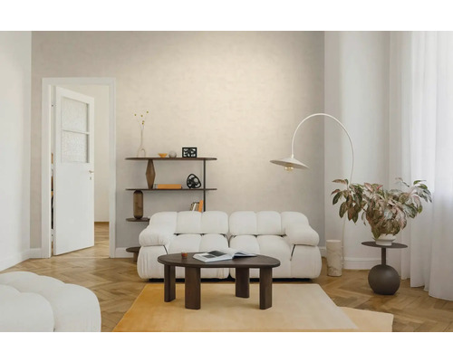 Licht ingerichte woonkamer met een witte gestoffeerde bank, een donkere houten salontafel, een booglamp en een visgraatparketvloer.