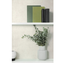 Vliesbehang met subtiele structuur in lichtbeige achter een witte plank met boeken en een vaas met eucalyptus takken.