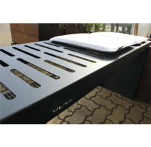 Detailopname van een grijze metalen barbecue met ventilatiesleuven en wit kussen