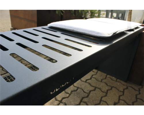 Detailopname van een grijze metalen barbecue met ventilatiesleuven en wit kussen