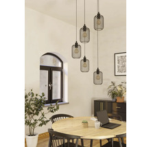 Eetkamer met houten tafel, stoelen en een hanglamp met meerdere zwarte lampenkappen