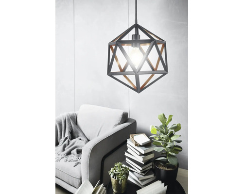 Metalen hanglamp met geometrisch ontwerp boven een fauteuil en een bijzettafel in de woonkamer.