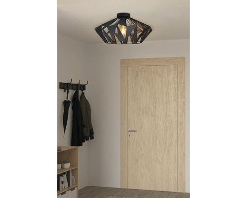 Metalen plafondlamp in de hal met kapstok en houten deur