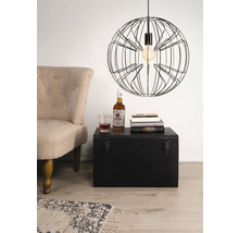 Scène met een fauteuil, een zwarte kist, boeken, een drankje en een hanglamp met draadframe.