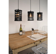 Drie zwarte hanglampen boven een gedekte eettafel.