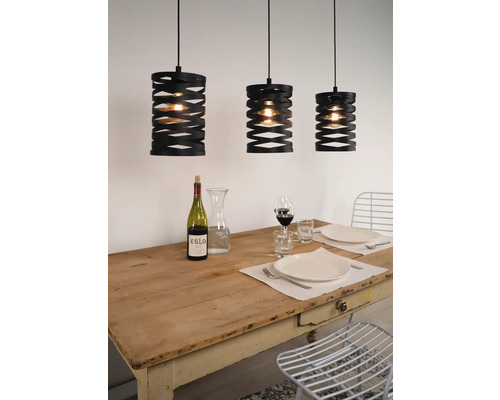 Drie zwarte hanglampen boven een gedekte eettafel.