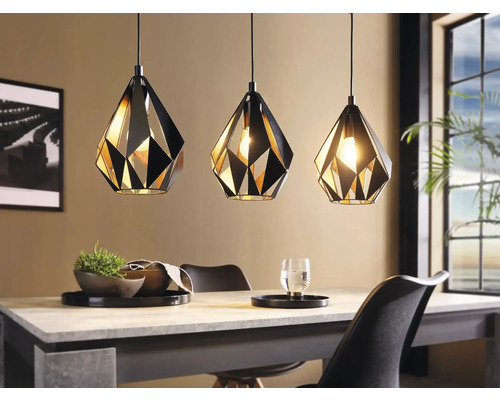 Drie geometrische hanglampen van metaal boven een eettafel