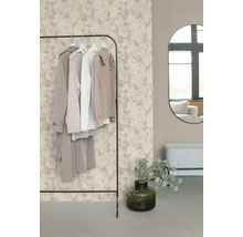 Vliesbehang met romantisch rozenpatroon in beige en roze achter een kledingrek in een modern ingerichte kleedkamer.