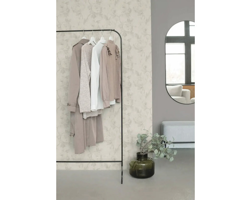 Licht ingerichte, georganiseerde kamer met vliesbehang met bloemmotief, metalen kledingrek, ovale wandspiegel en een bankje.