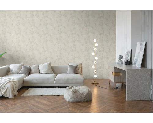 Lichte woonkamer met vliesbehang met bloemenpatroon, houten visgraatvloer, moderne bank en een vloerlamp.