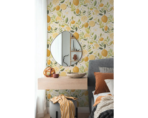 Vliesbehang met citroenpatroon in een slaapkamer met organische spiegel, zwevend nachtkastje en grijs gestoffeerd bed.