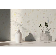 Vliesbehang met fijn floraal patroon van grassen en bloemen in aquarelstijl, gecombineerd met vazen in een lichte kamer.