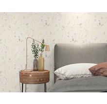 Lichte slaapkamer met behang met bloemenpatroon, grijs gestoffeerd bed, rond houten nachtkastje en moderne metalen tafellamp.