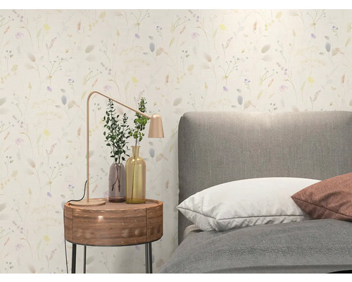 Lichte slaapkamer met behang met bloemenpatroon, grijs gestoffeerd bed, rond houten nachtkastje en moderne metalen tafellamp.